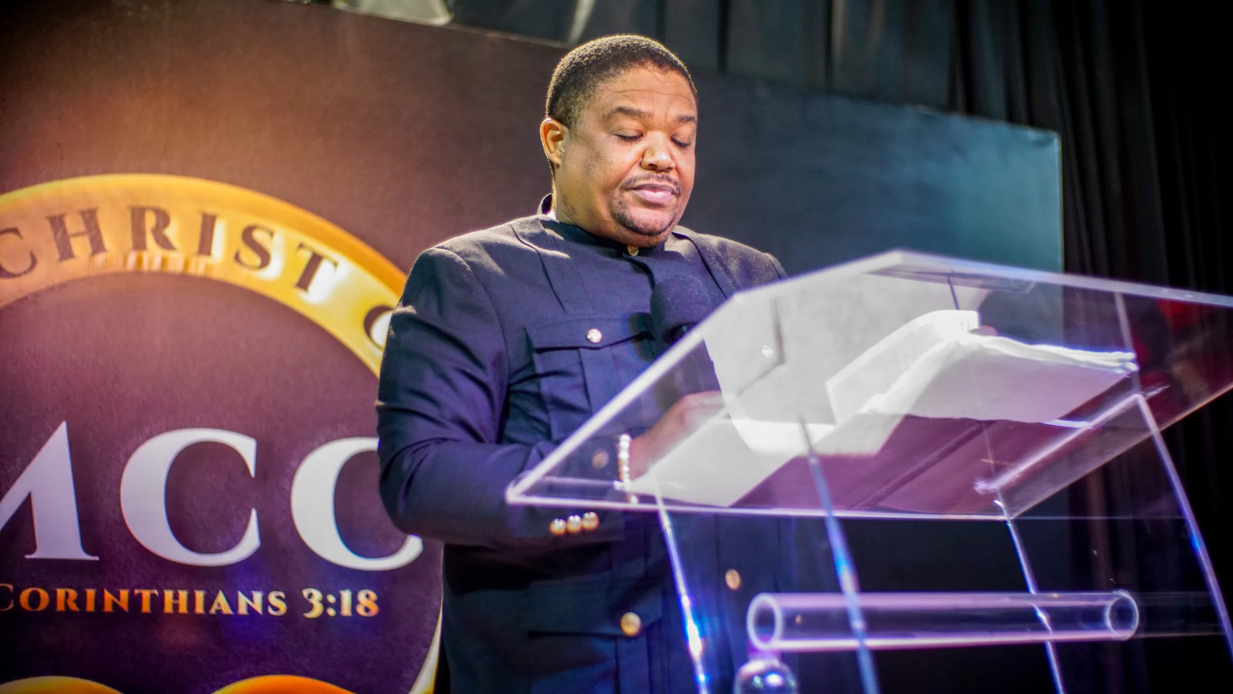 A pastor of Mirror Christ Church at the lectern, head bowed